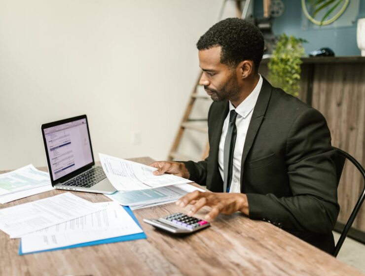 Business professional reviewing financial compliance documents and payroll paperwork at a desk