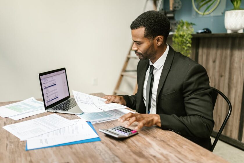 Business professional reviewing financial compliance documents and payroll paperwork at a desk
